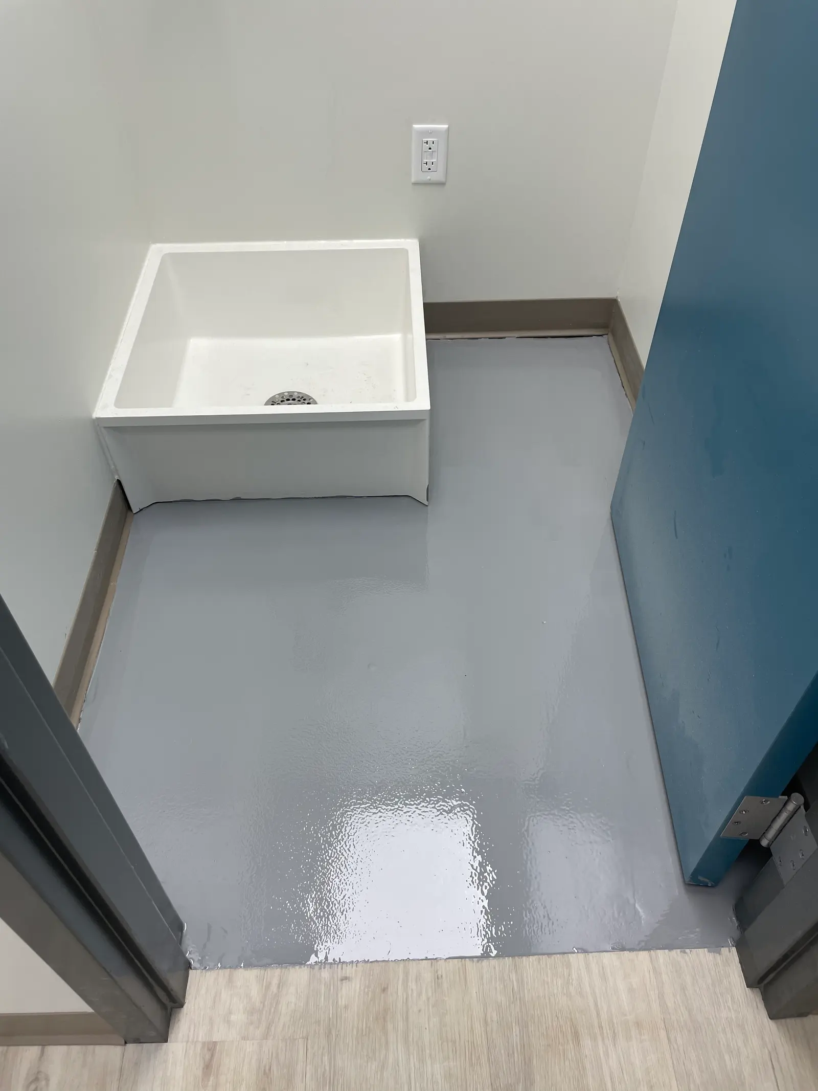 Commercial utility room with a high-gloss solid gray epoxy floor around a mop sink