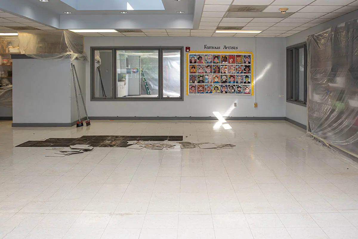 Commercial interior mid-demolition with old tile partially removed from the slab