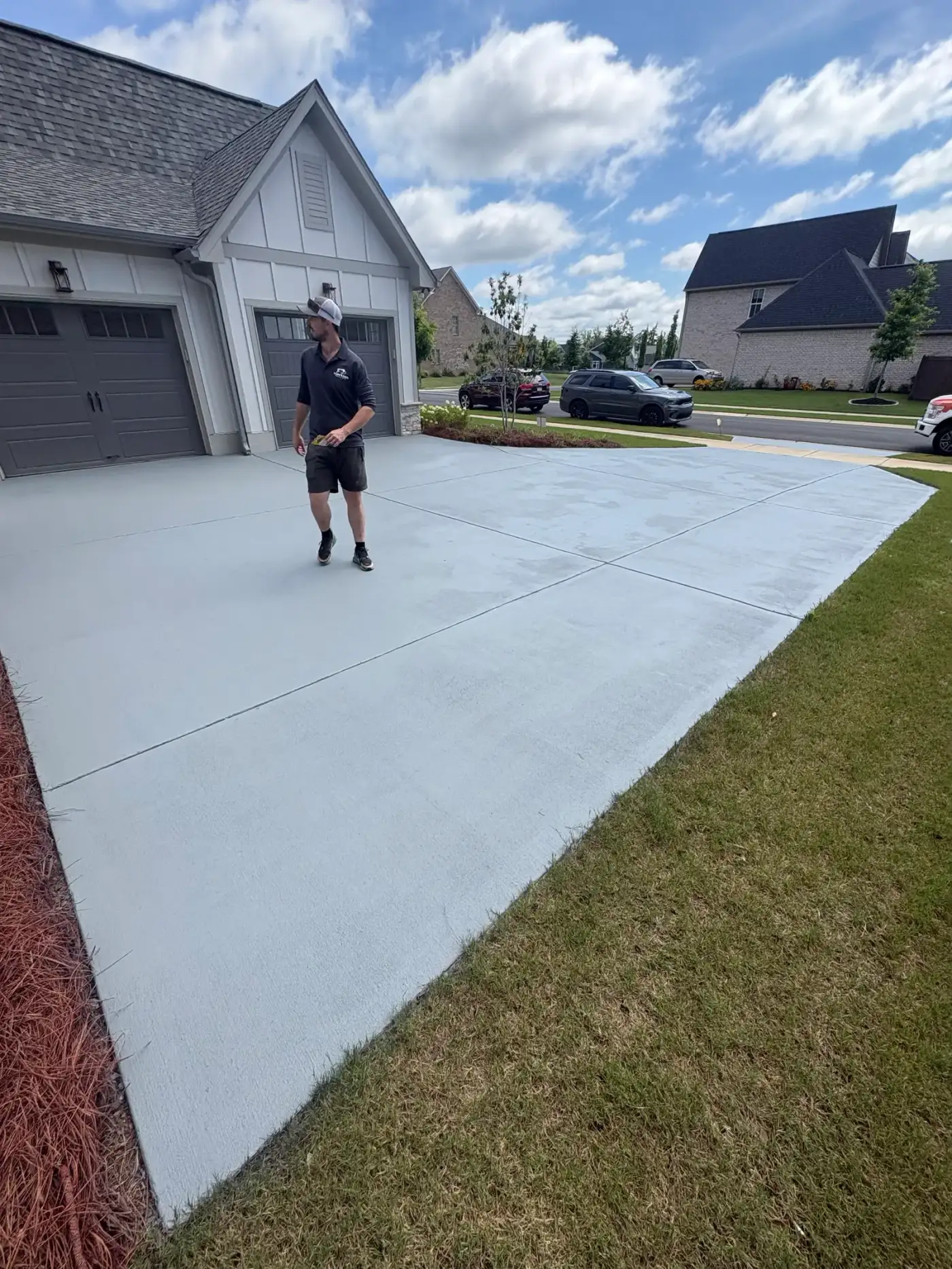 Installer walking a freshly coated light gray driveway on final walkthrough