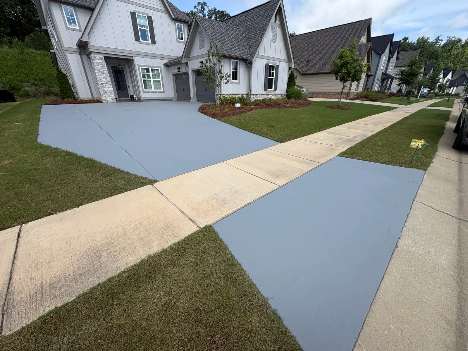 Full driveway in solid gray broadcast coating on both sides of the sidewalk