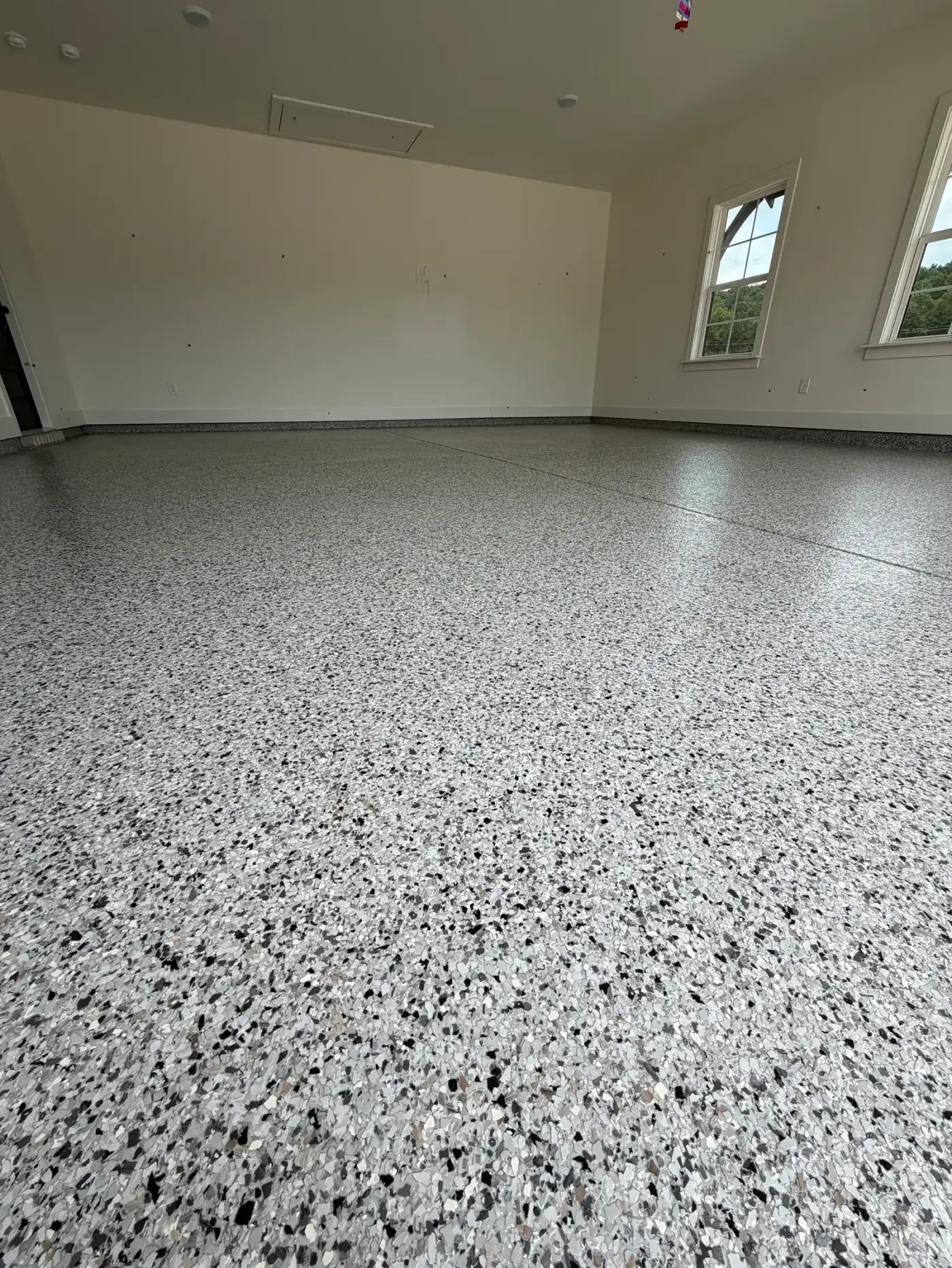 Full-broadcast vinyl flake floor under a clear topcoat, shot low across the surface