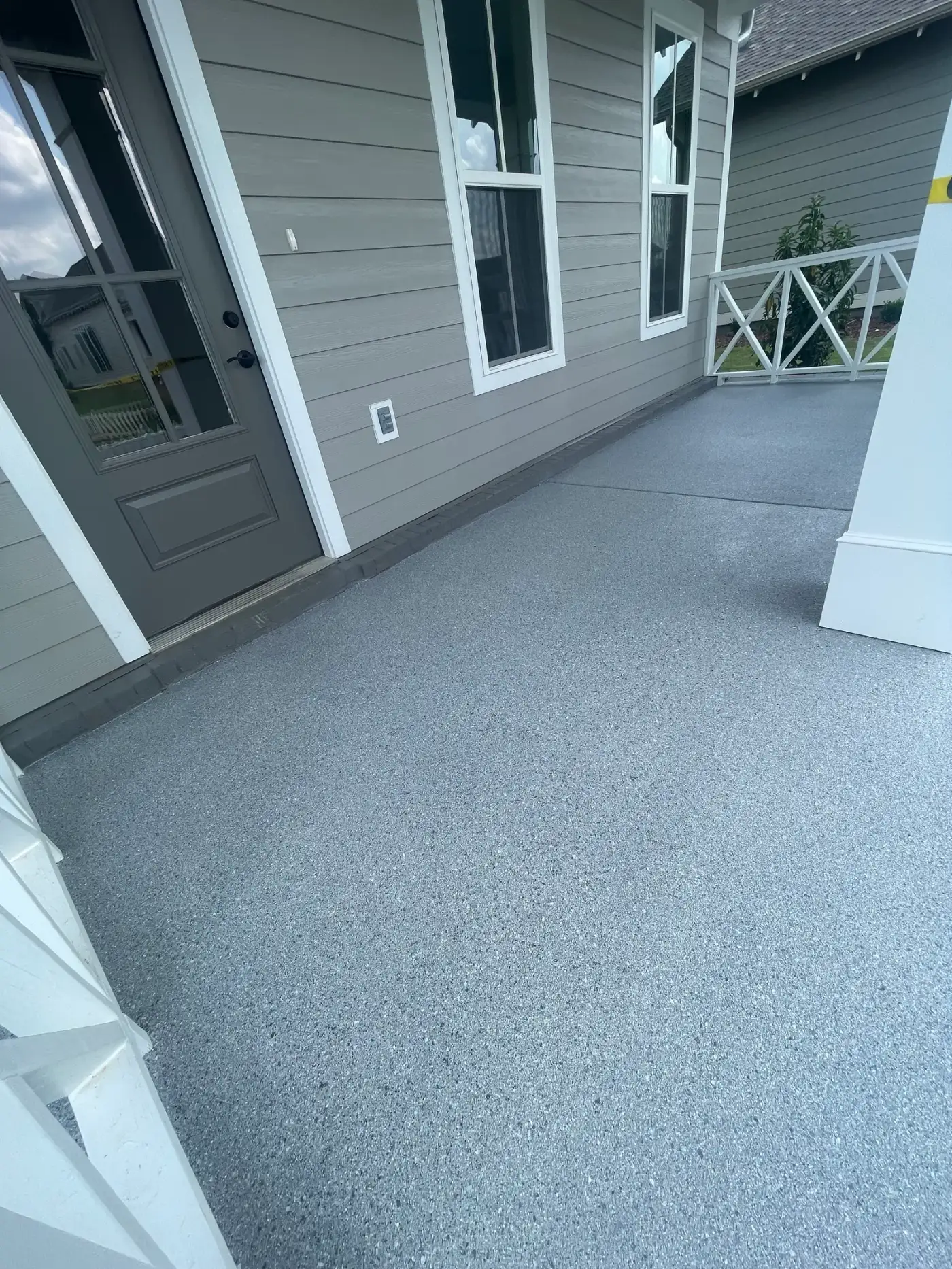 Covered front porch with a gray flake coating up to the entry door