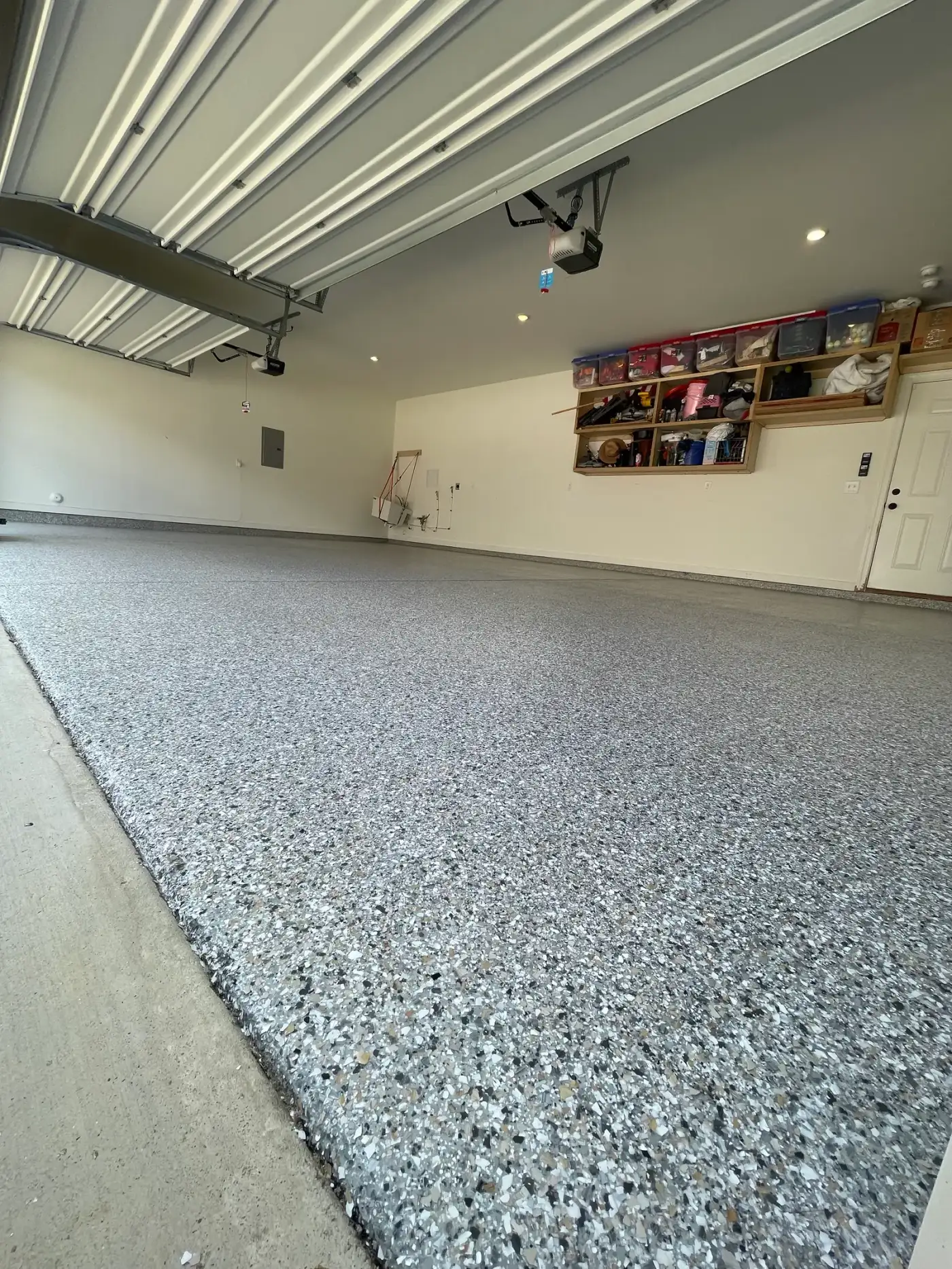 Working garage with a gray flake floor, storage shelves and gear on the walls
