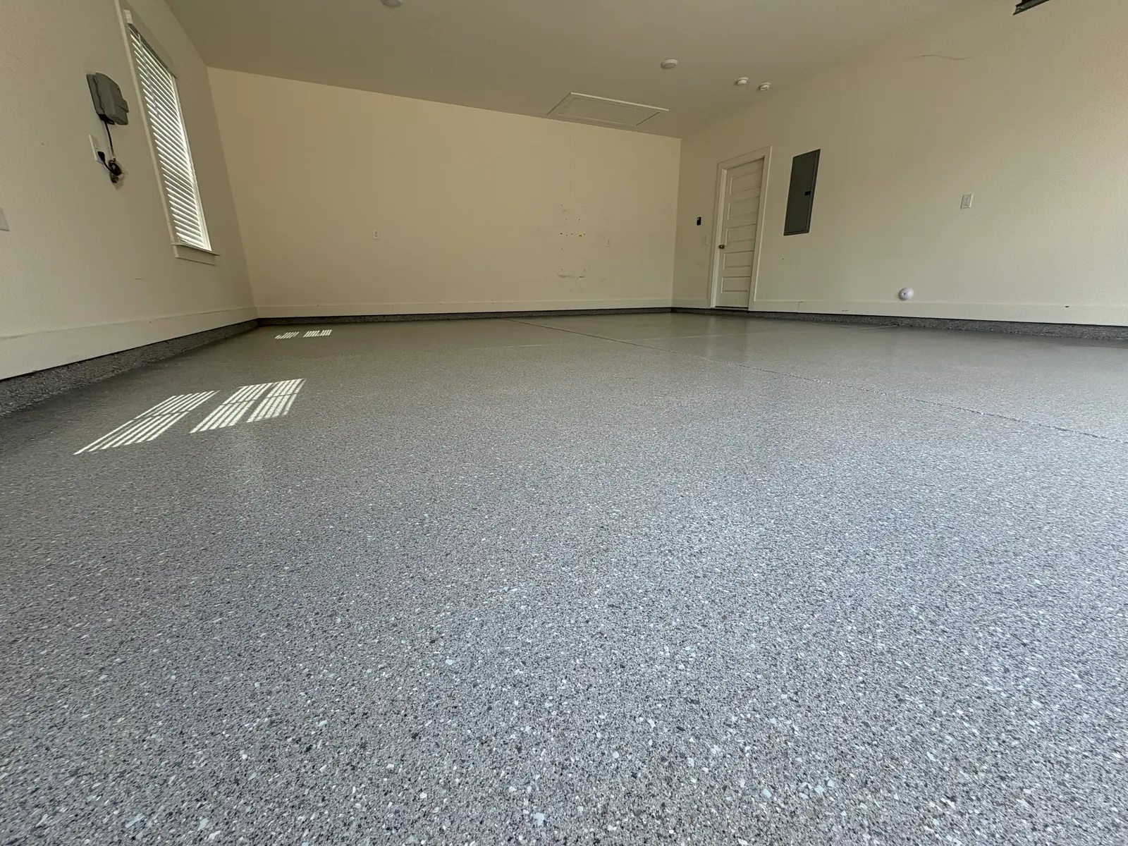 Three-car garage with a dark charcoal flake-coated floor, freshly installed