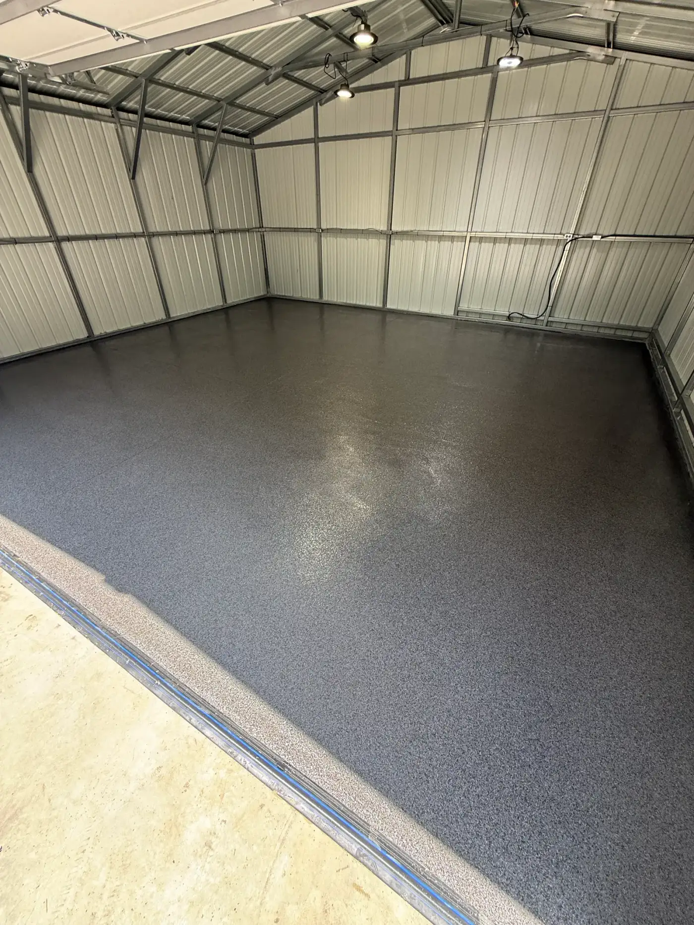 Metal outbuilding with a dark textured coating across the slab