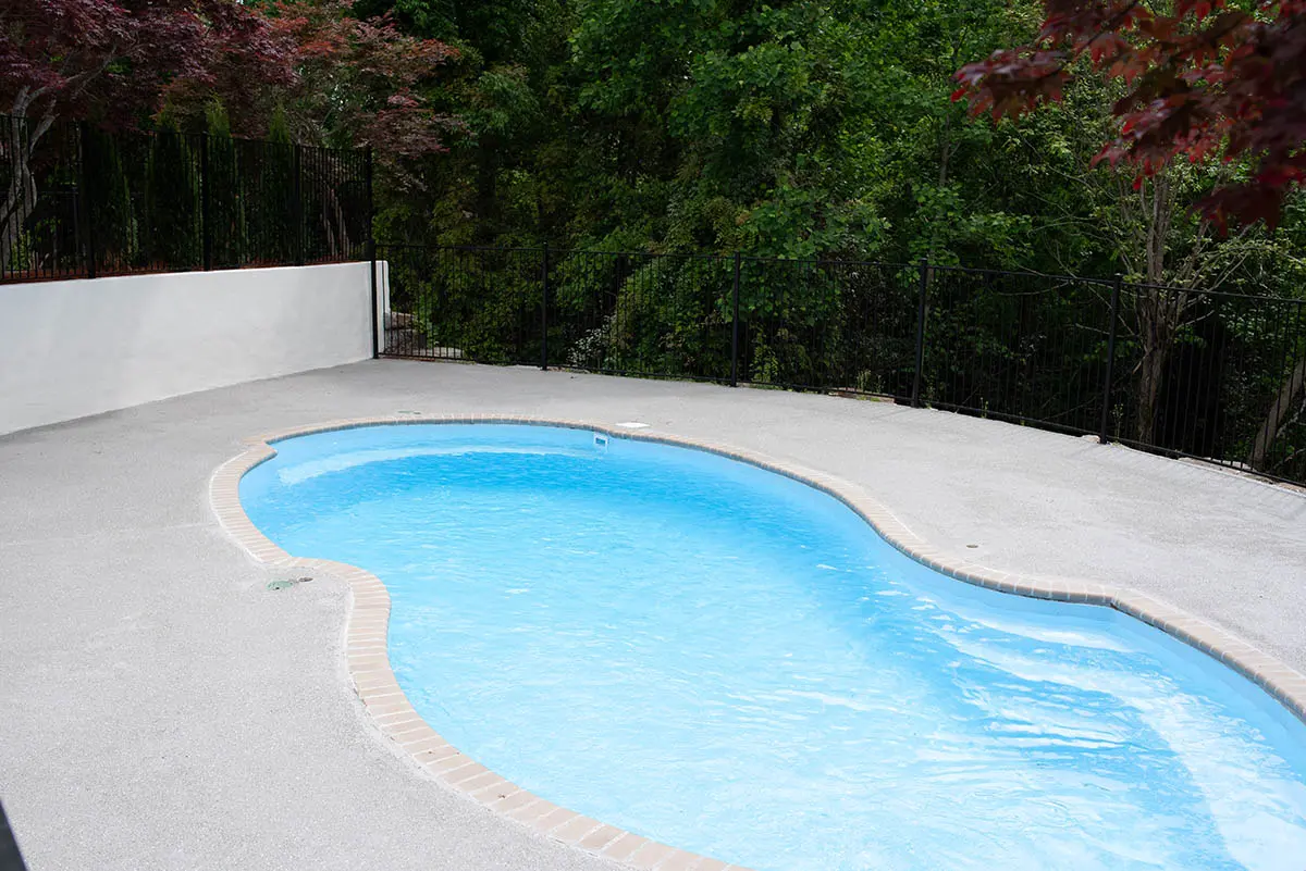 Residential pool with a light gray cool-touch deck coating around the waterline