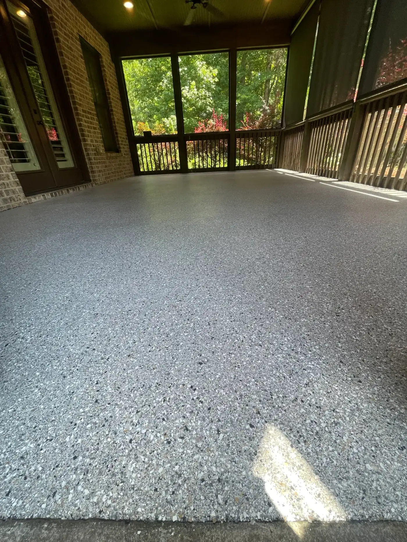 Screened porch with a light gray flake coated floor overlooking trees